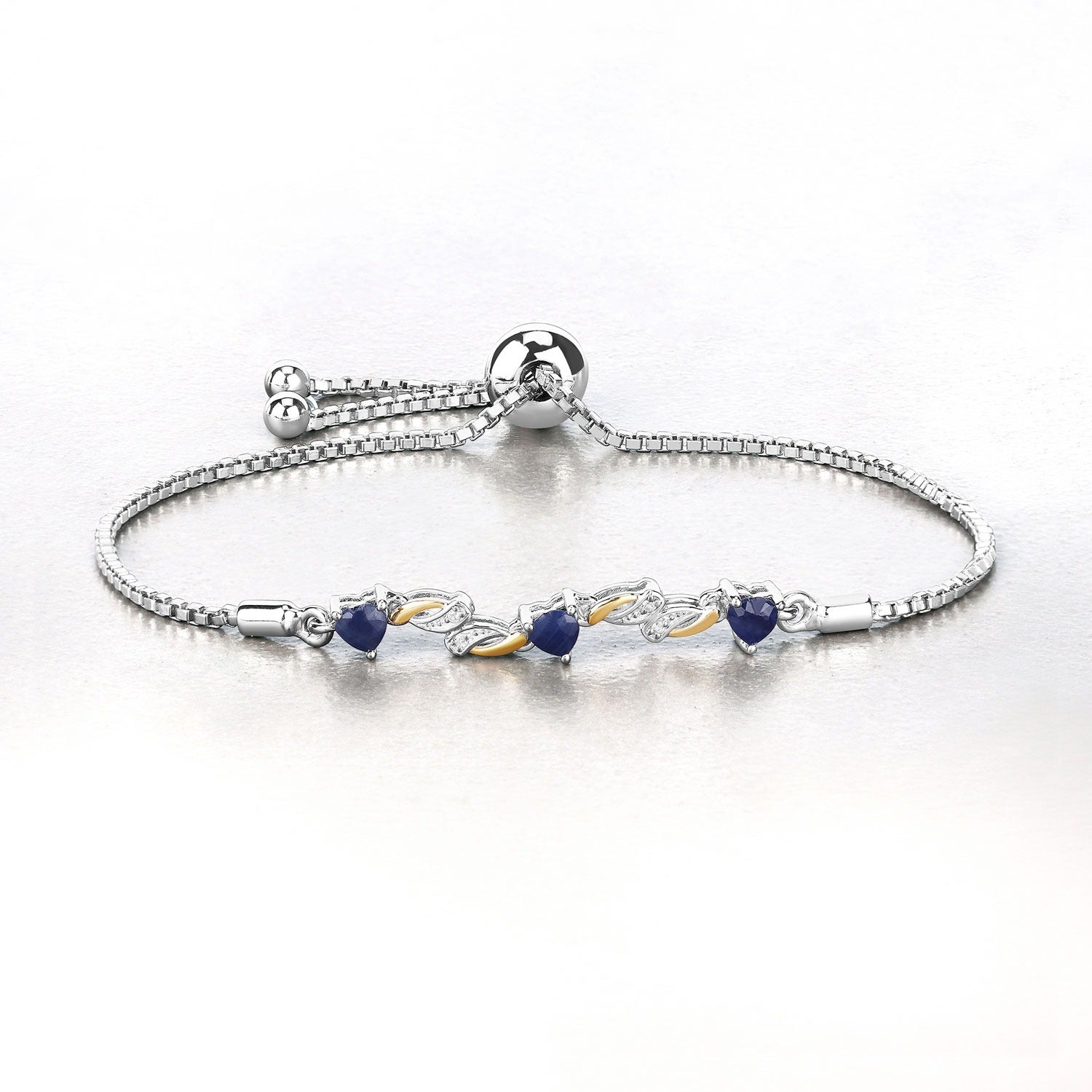 Silver adjustable bracelet with blue sapphire gemstones and gold leaf accents on white background