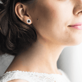 Model showcasing Natural Sapphire Halo Earrings With Moissanite Accents White Gold and Light Blue Halo Stud Earrings