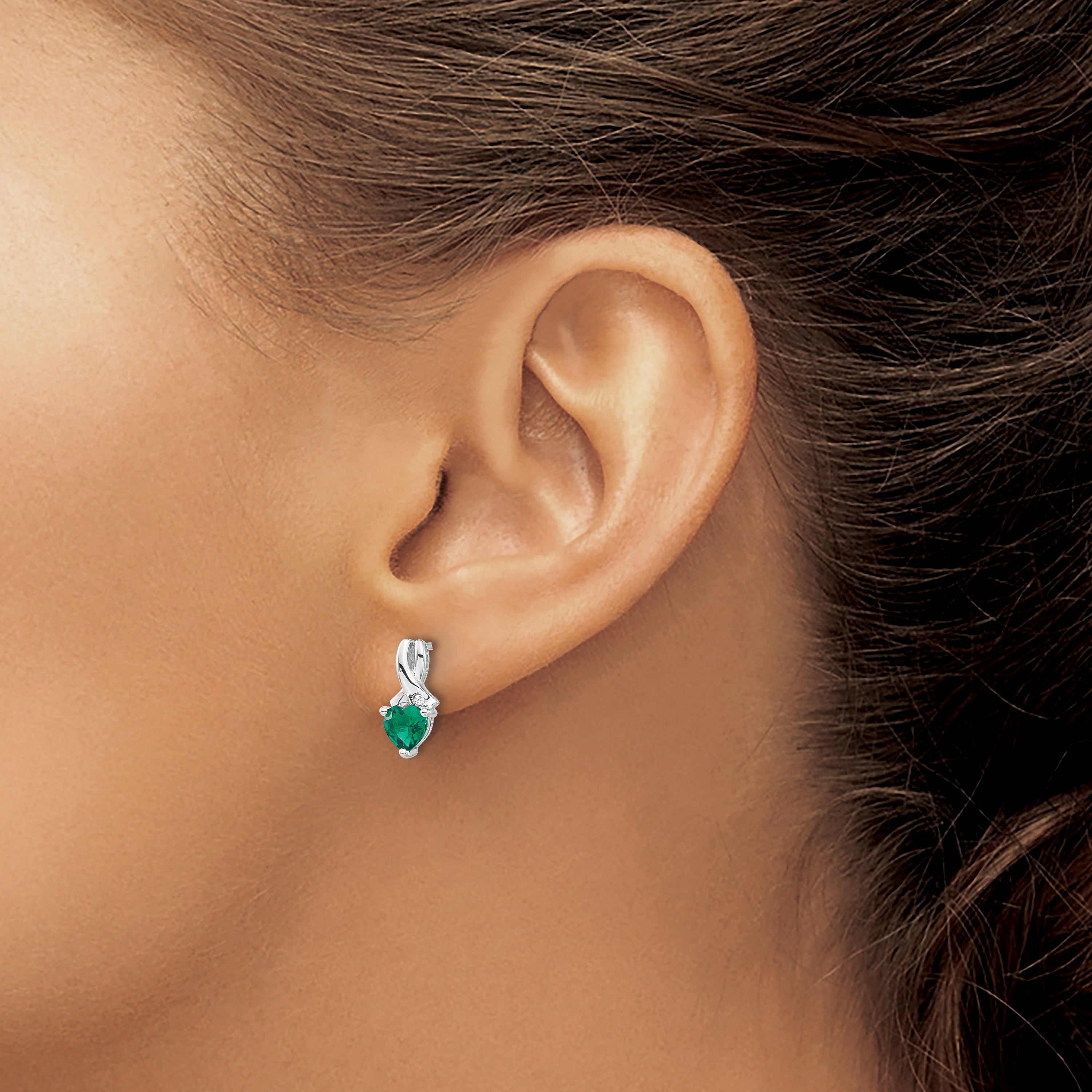 Woman wearing a silver earring with green gemstone, close-up on ear jewelry